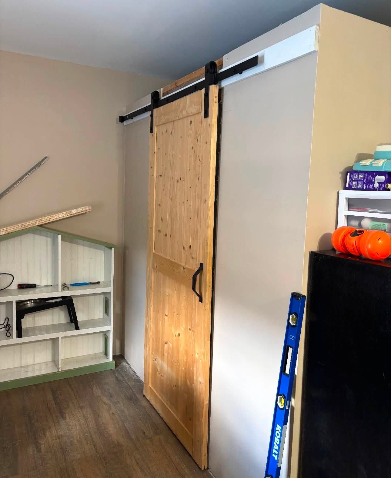 Barn door installed in a room corner beside a level and shelving
