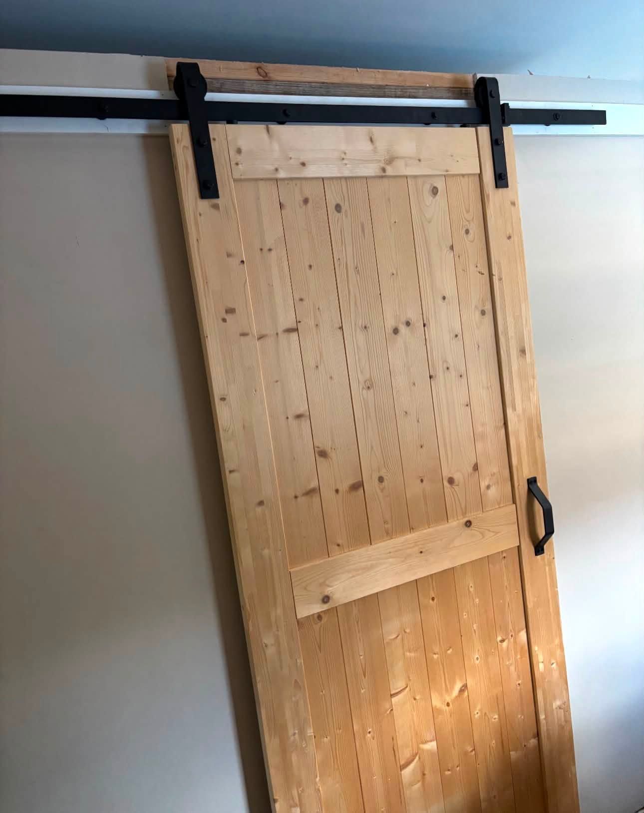 Natural pine barn door with Z-brace on black sliding track