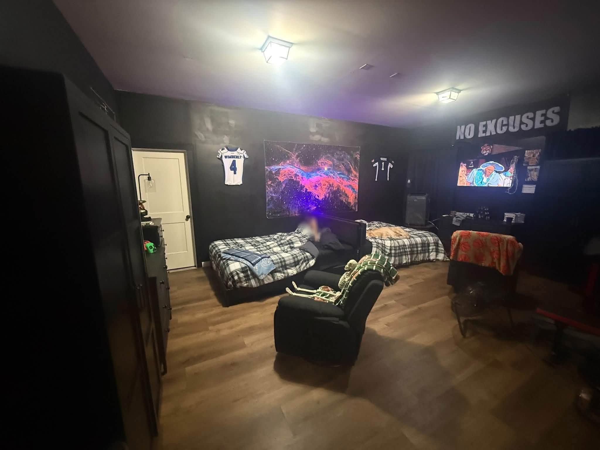 Finished bedroom with dark painted walls, wood-look floor and furniture moved in