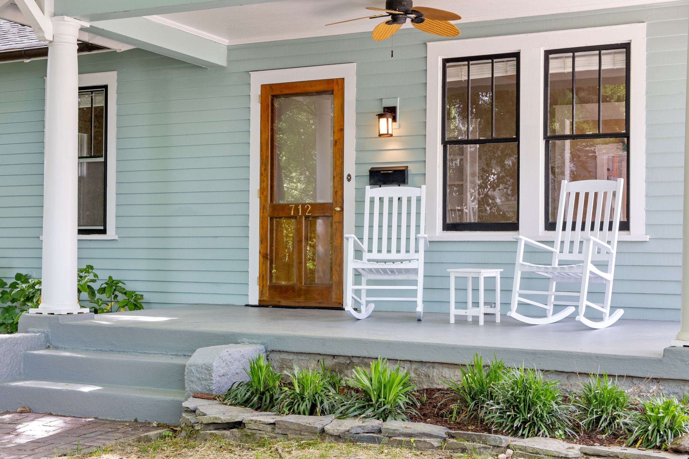 Front porch with white rocking chairs and a wooden front door