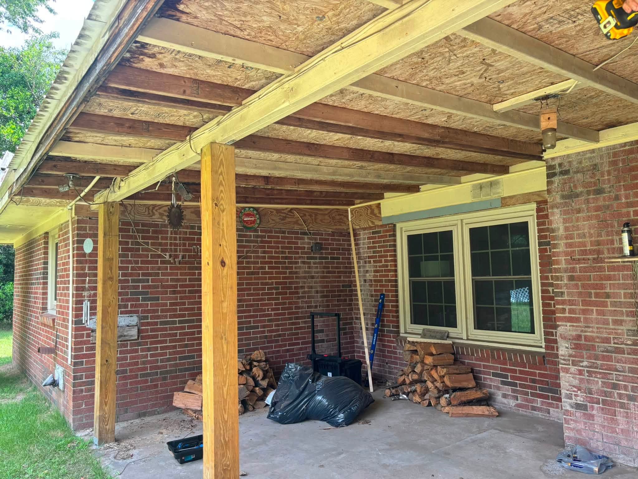 Before: looking down the covered porch at open framing and bare wood posts