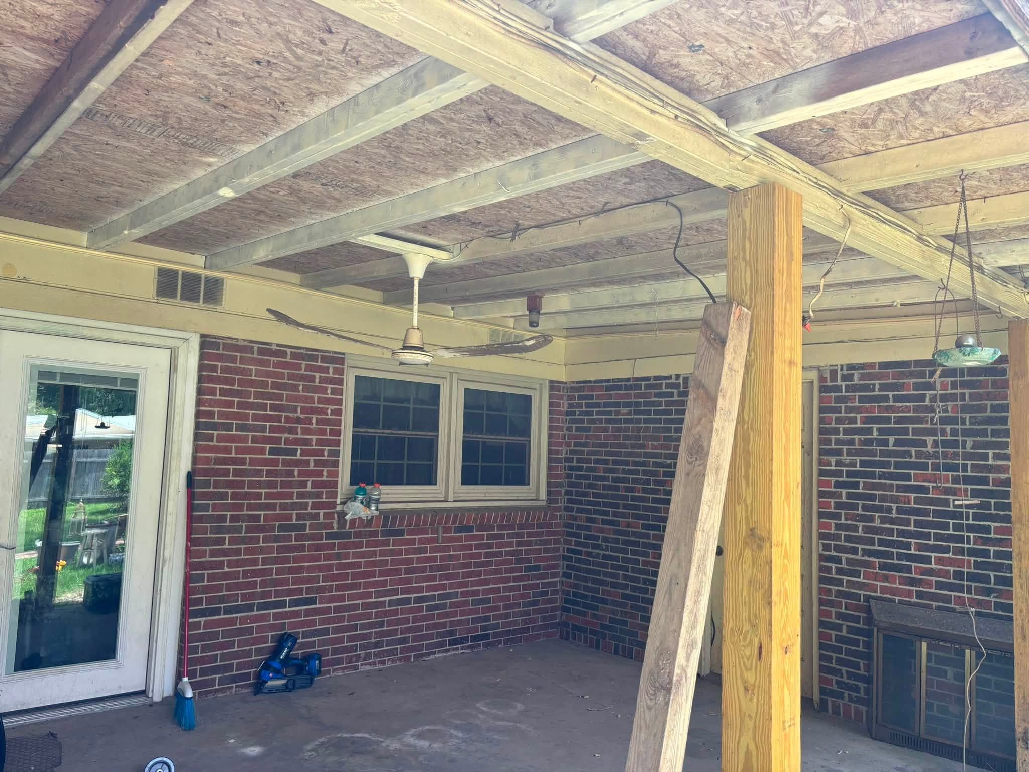 Porch before: exposed rafters and open joists above a brick back patio