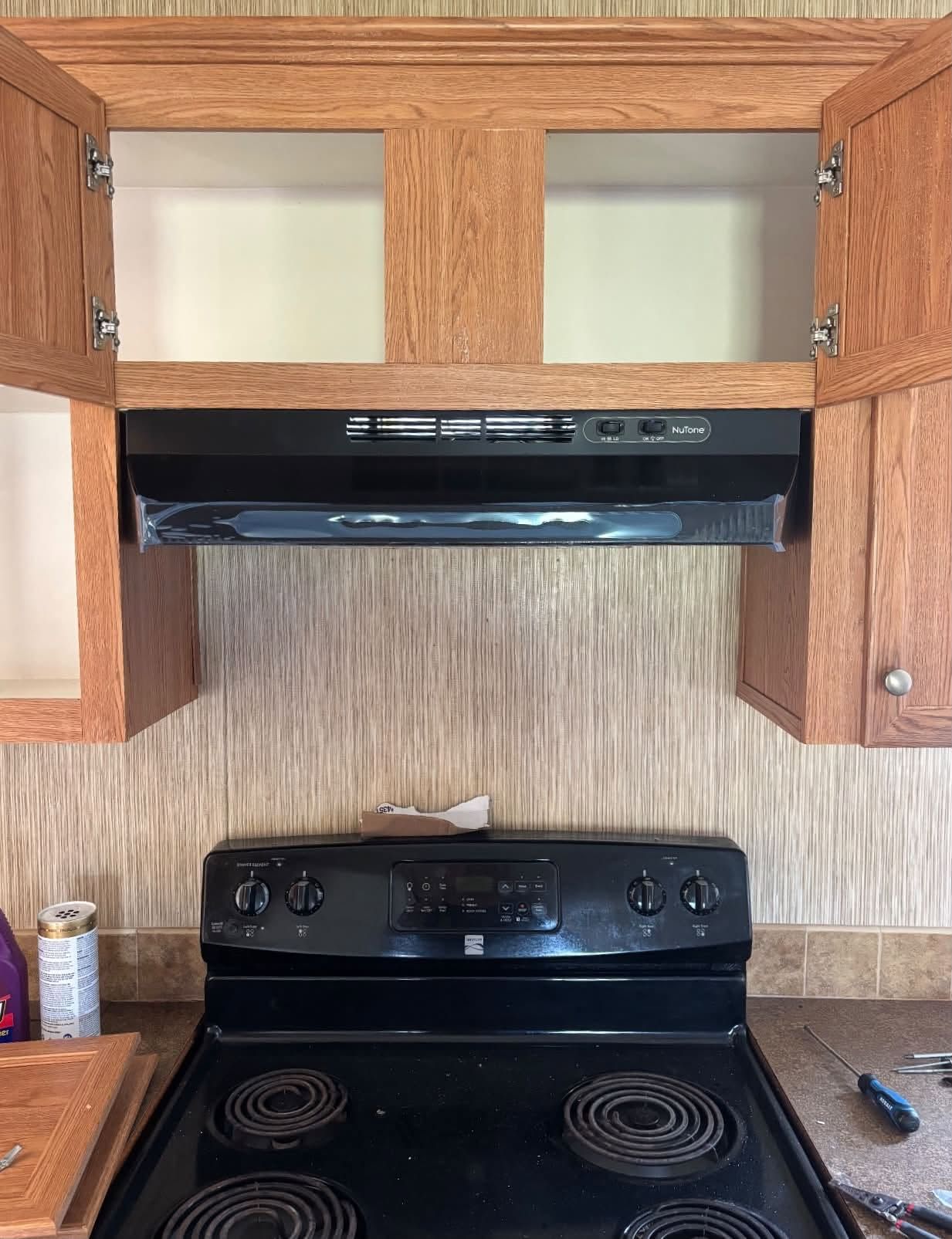 New black under-cabinet range hood installed above an electric stove